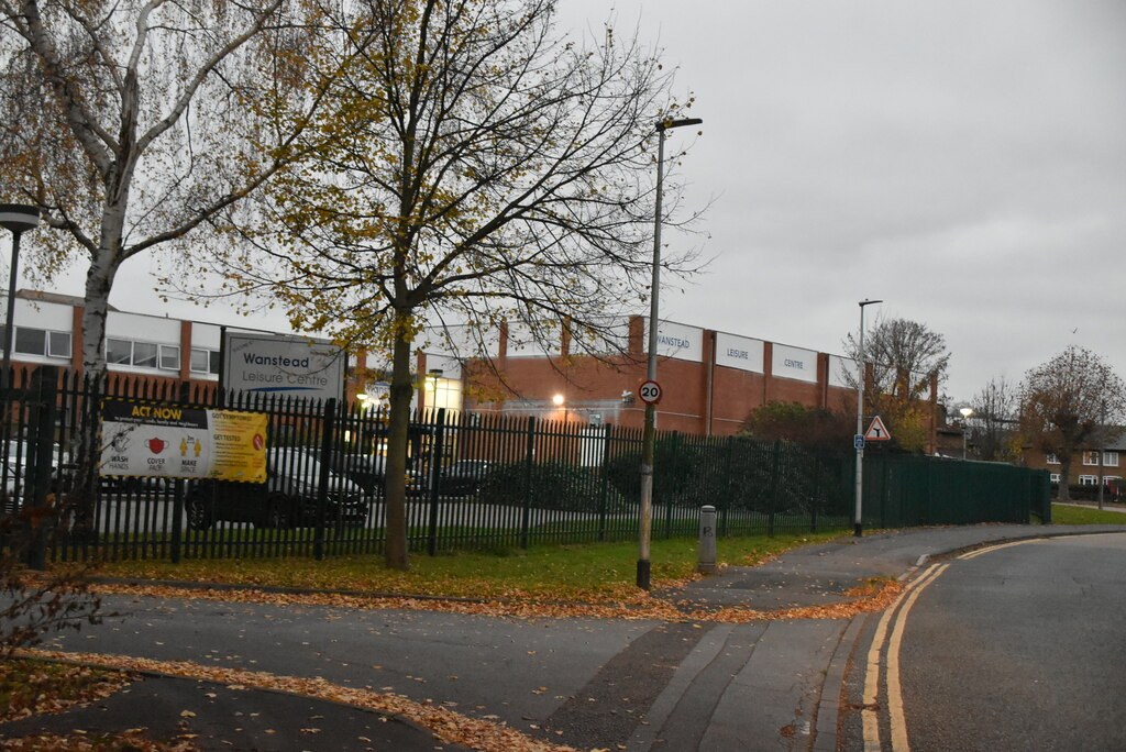 The red-brick Wanstead Leisure Centre behind railings, seen from the road