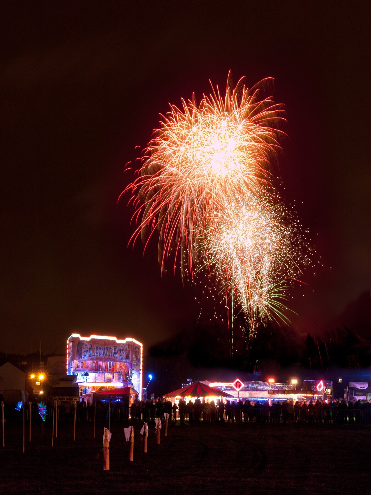 A firework bursting above a fairground at night