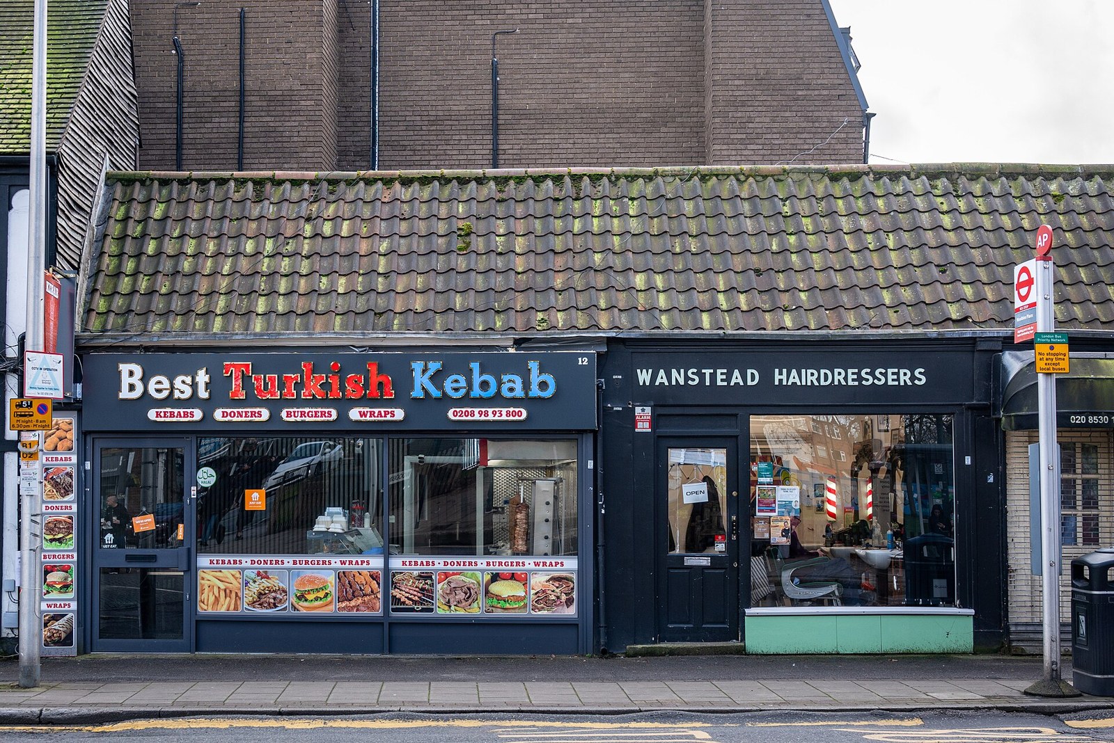 The single-storey shopfronts on Woodbine Place, including a kebab shop and a hairdresser