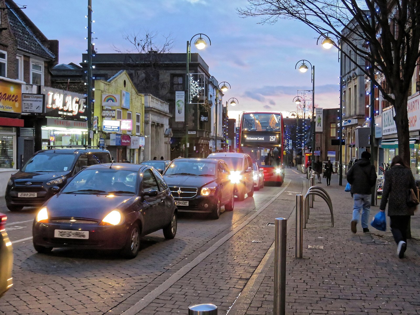 Christmas lights strung above a busy high street at dusk