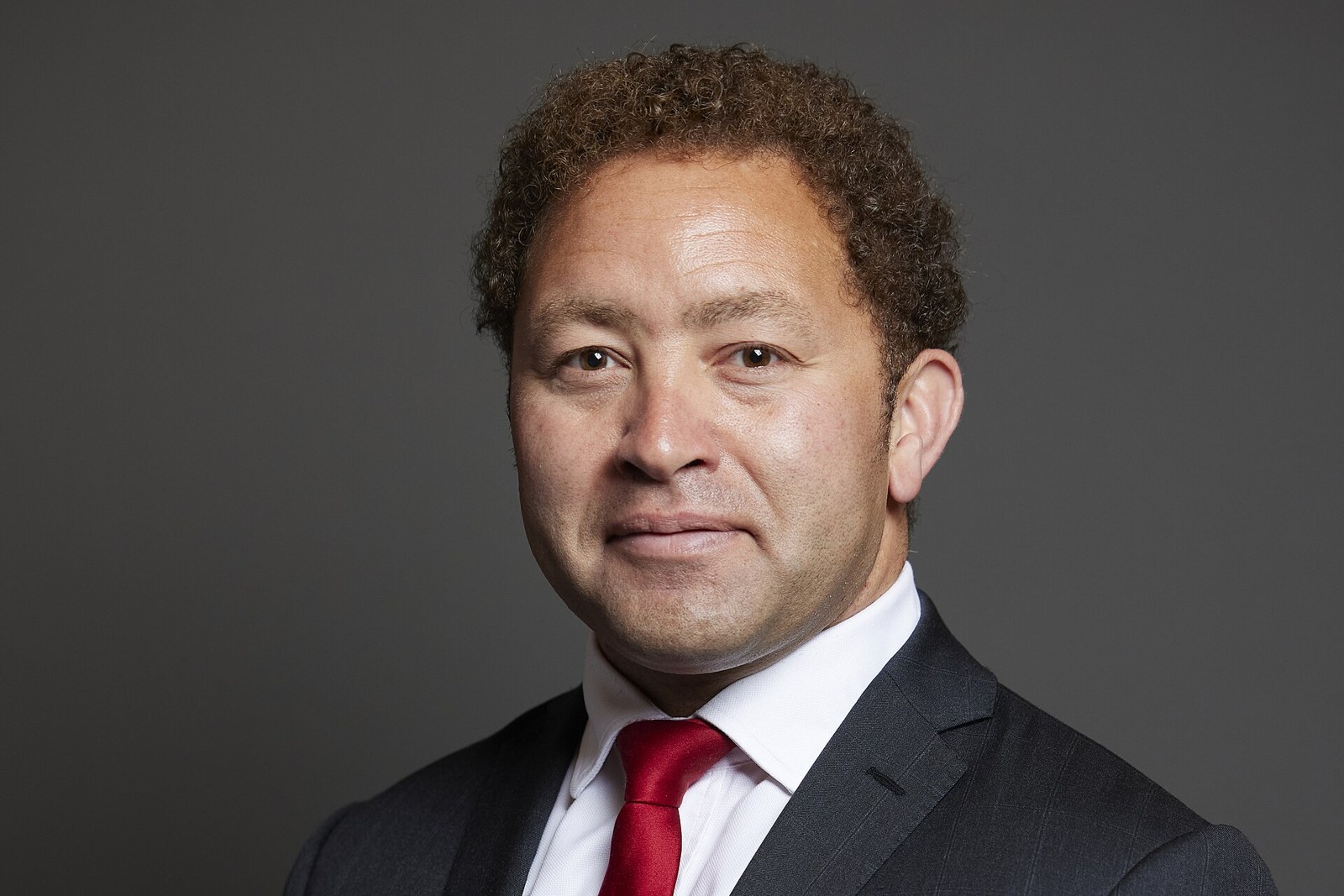 Official portrait of Calvin Bailey MP in a dark suit and red tie