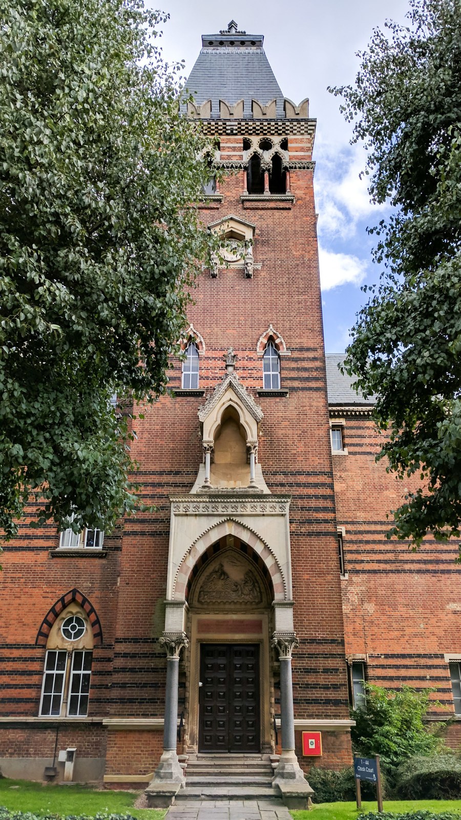 The clock tower of the former asylum seen from the front, with its pointed arched porch below